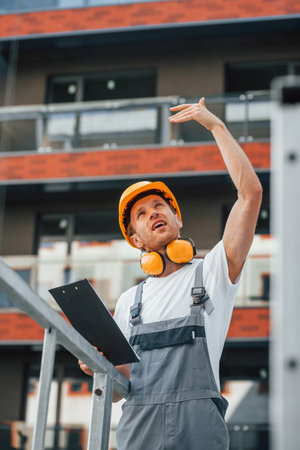 Unfinished project. Young man working in uniform at construction at daytimeの写真素材