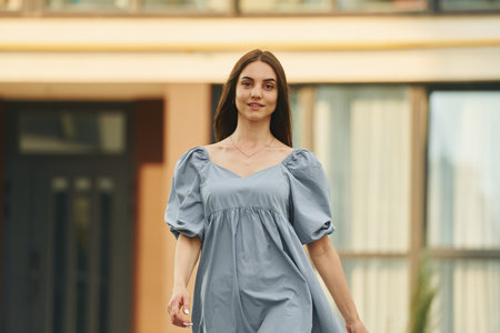 Beautiful young woman walking in dress in the city. Building exteriorの写真素材