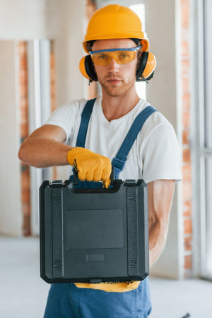 Modern repair. Young man working in uniform at construction at daytimeの写真素材