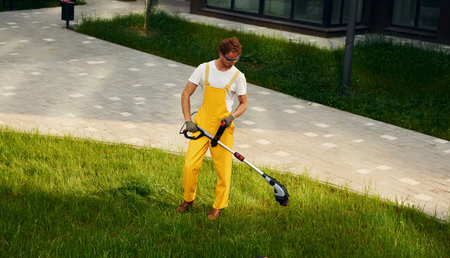 Distant view. Man cut the grass with lawn mover outdoors in the yard
