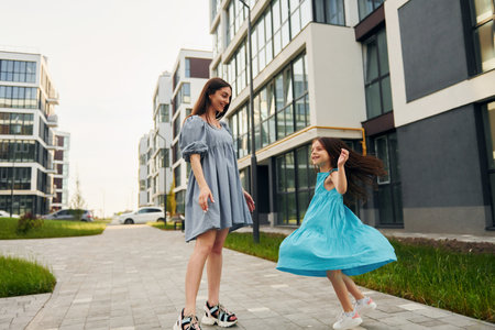 Young mother with her little daughter walking near the buildingsの写真素材