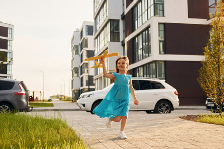 Cheerful little girl walking outdoors in the city in dressの写真素材