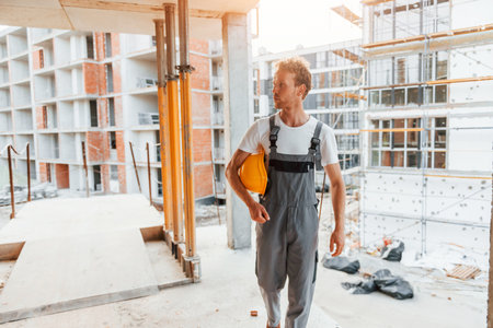 Big project. Young man working in uniform at construction at daytimeの写真素材