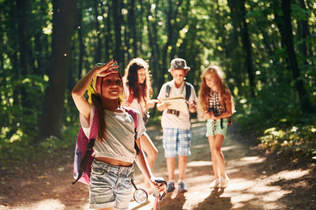 Girl looking far away. Kids strolling in the forest with travel equipmentの写真素材