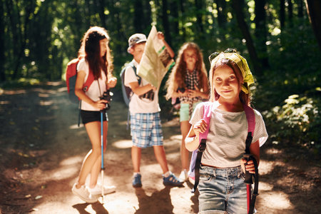 Posing for the camera. Kids strolling in the forest with travel equipmentの写真素材