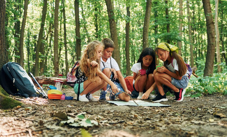 Sitting on the ground. Kids strolling in the forest with travel equipmentの写真素材
