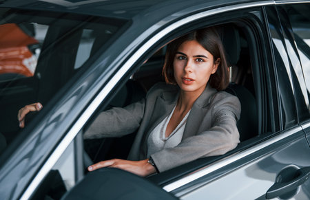 Woman testing new car. Sitting indoors in modern automobileの写真素材