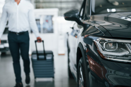 Partical view. Man in formal clothes is with luggage indoors near the carの写真素材