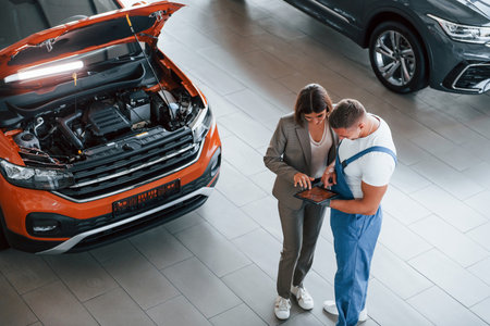 Two people. Man repairing womans automobile indoors. Professional serviceの写真素材