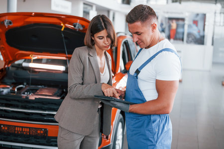 Two people. Man repairing womans automobile indoors. Professional serviceの写真素材