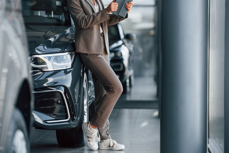 Particle view. Woman is indoors near brand new automobile indoorsの写真素材