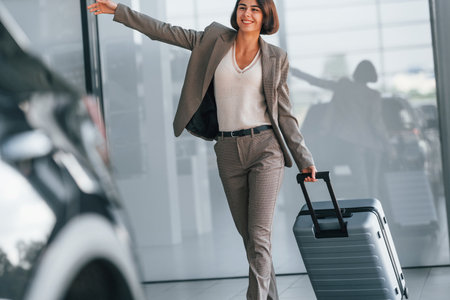Happy woman with luggage is standing indoors. Conception of tourismの写真素材