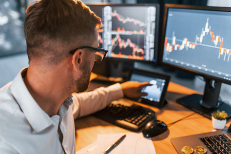 Many monitors. Young businessman in formal clothes is in office with multiple screensの写真素材