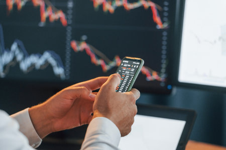 Busy young businessman in formal clothes is in office with multiple screensの写真素材