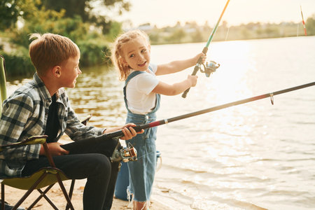 Medium sized lake. Boy with his sister in on fishion outdoors at summertime togetherの写真素材
