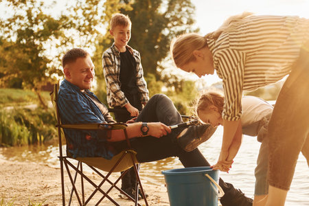 Big catch. Father and mother with son and daughter on fishing together outdoors at summertimeの写真素材
