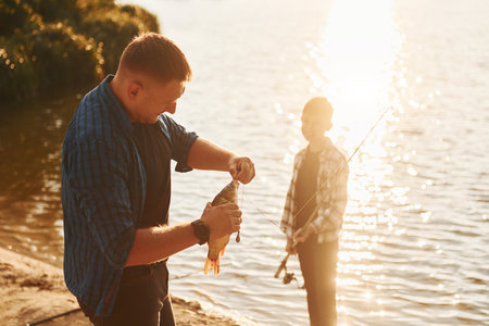 With catch. Father and son on fishing together outdoors at summertimeの写真素材