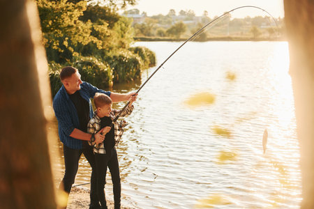 Some food to eat. Father and son on fishing together outdoors at summertimeの写真素材