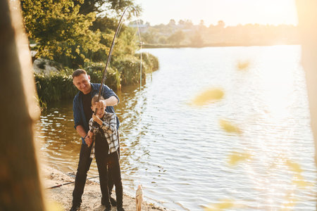 Some food to eat. Father and son on fishing together outdoors at summertimeの写真素材