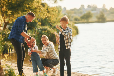 At summertime. Father and mother with son and daughter on fishing together outdoorsの写真素材