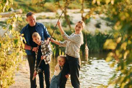 Father and mother with son and daughter on fishing together outdoors at summertimeの写真素材