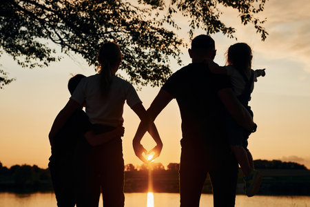 Looking at sunset. Family of mother, father and kids is on the campingの写真素材