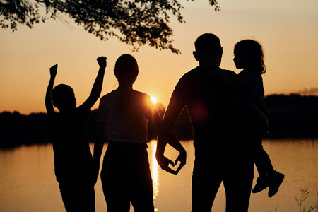 Looking at sunset. Family of mother, father and kids is on the campingの写真素材