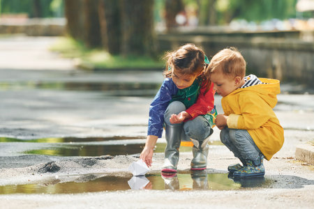 In the puddle. Kids having fun outdoors in the park after the rainの写真素材