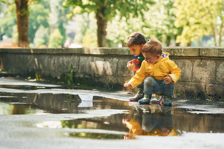 In the puddle. Kids having fun outdoors in the park after the rainの写真素材