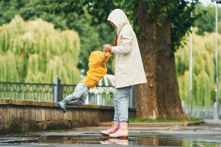 Having fun. Mother with her son is having a walk outdoors in the park after the rainの写真素材