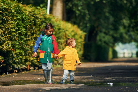 Walking together. Kids having fun outdoors in the park after the rainの写真素材