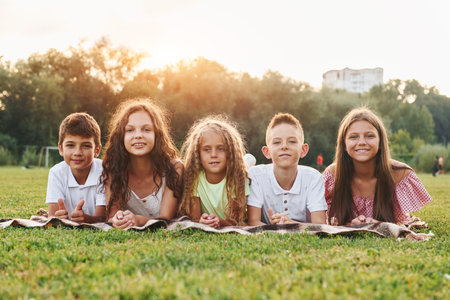 Front view. Group of happy kids is outdoors on the sportive field at daytimeの写真素材