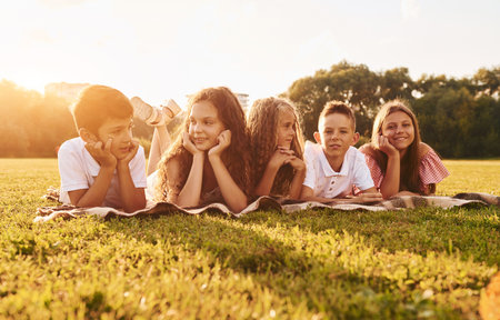 Having fun. Group of happy kids is outdoors on the sportive field at daytimeの写真素材