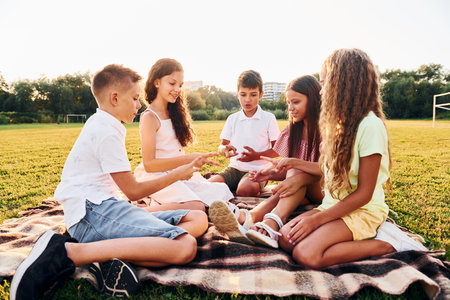 Playing games. Group of happy kids is outdoors on the sportive field at daytimeの写真素材