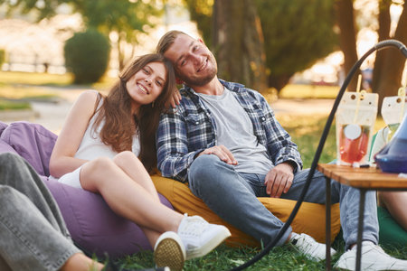 Happy couple. Group of young people have a party in the park at summer daytimeの写真素材