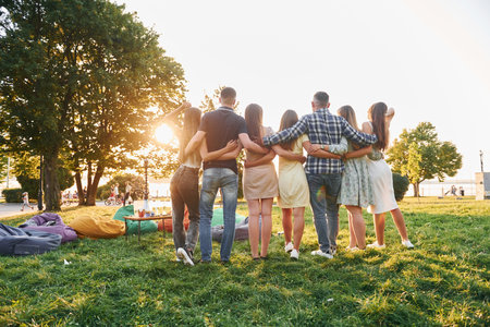 View from behind. Group of young people have a party in the park at summer daytimeの写真素材