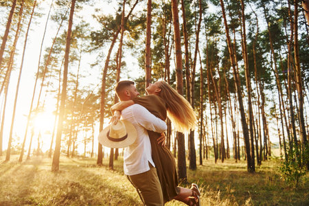 Against background with sunshine. Happy couple is outdoors in the forest at daytimeの写真素材
