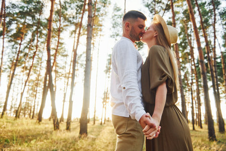 Holding each other by the hands. Happy couple is outdoors in the forest at daytimeの写真素材