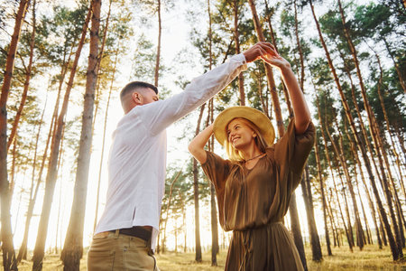 Holding each other by the hands. Happy couple is outdoors in the forest at daytimeの写真素材