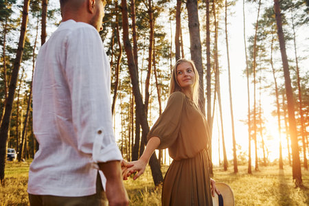 Follow me, concept. Happy couple is outdoors in the forest at daytimeの写真素材