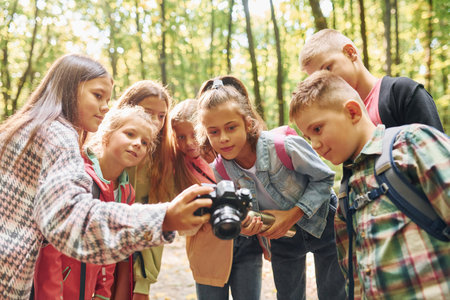 Front view. Kids in green forest at summer daytime togetherの写真素材