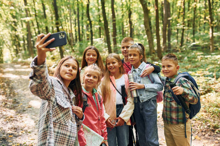 Front view. Kids in green forest at summer daytime togetherの写真素材