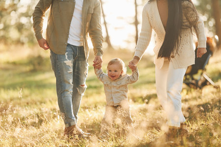 Having a walk. Happy family of father, mother and little daughter is in the forestの写真素材