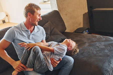 Positive emotions. Father and son is indoors at home togetherの写真素材