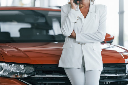 Using phone. Woman in formal clothes is indoors in the autosalonの写真素材