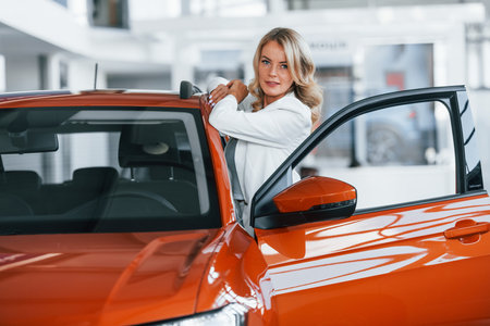 Opening the door. Woman in formal clothes is indoors in the autosalonの写真素材