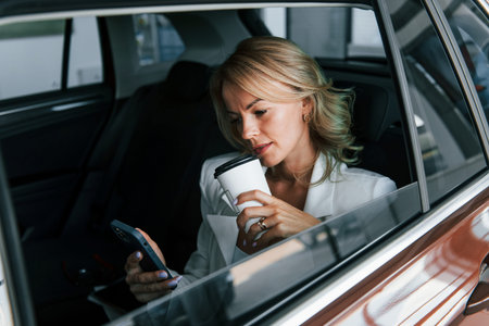 Side view. Woman in formal clothes is indoors in the autosalon