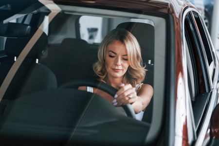 Comfortable car. Woman in formal clothes is indoors in the autosalonの写真素材