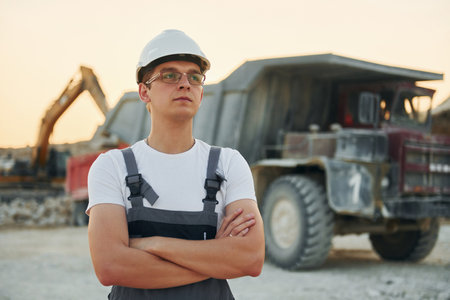 Near loading vehicle. Worker in professional uniform is on the borrow pit at daytimeの写真素材
