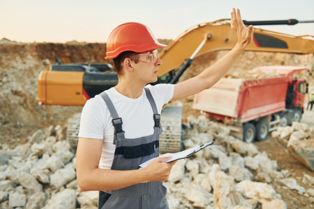 Management of project. Worker in professional uniform is on the borrow pit at daytimeの写真素材
